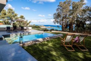 a backyard with a swimming pool and two lawn chairs at Luxury Villa Mon II Vassilikos in Vasilikos