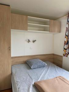 Dormitorio pequeño con cama y armarios de madera en Mobil-home mitoyen 1 chambre 