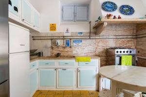 uma cozinha com armários brancos e uma mesa em Lanui Guest House em Sintra