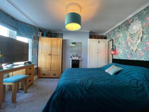 a bedroom with a blue bed and a television at Large Room sleeps 3 own TV and cereal and toast breakfast in Newhaven in Tarring Neville