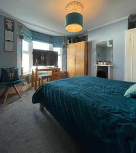a bedroom with a large bed with a blue blanket at Large Room sleeps 3 own TV and cereal and toast breakfast in Newhaven in Tarring Neville