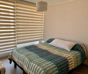 a bedroom with a bed and a window with blinds at Departamento nuevo, vista al Mar, Reloj de Flores in Viña del Mar