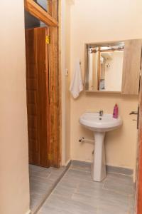 a bathroom with a sink and a mirror at Arabella Apartments in Bungoma
