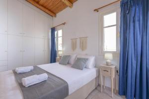 1 dormitorio con 1 cama grande y cortinas azules en Rethymno Heart, en Áyios Andónios