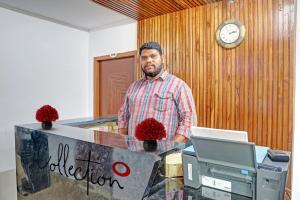 Un uomo in piedi davanti a una scrivania con un computer di Super OYO Capital O Vihari Grand Inn a Warangal