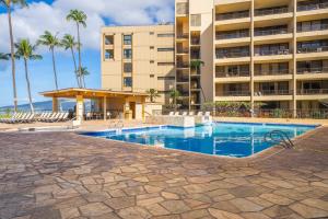 a swimming pool in front of a building at Sugar Beach Resort in Kihei