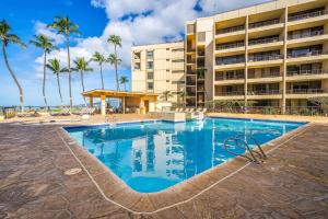 a swimming pool in front of a building with palm trees at Sugar Beach Resort in Kihei