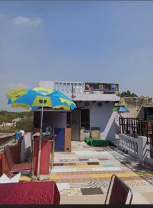 een patio met een parasol en stoelen en een gebouw bij Shiva guest House (hoche poche cafe ) in Agra