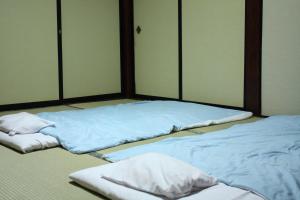 two beds in a room with blue sheets at Tamonkan in Tsuruoka
