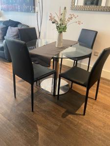 una mesa de comedor con 4 sillas y un jarrón con flores en JJ Luxury Apartment, en Londres