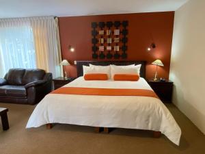 a bedroom with a large bed and a chair at Capital O La Huerta Golf & Hotel in Cholula