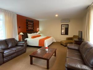 Habitación de hotel con cama y sofá en Capital O La Huerta Golf & Hotel en Cholula
