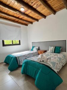 Depto. Caminos del Vino Mendoza Maipú في ميندوزا: غرفة نوم بسريرين وسقف خشبي