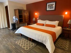 a bedroom with a large bed with orange walls at Capital O La Huerta Golf & Hotel in Cholula