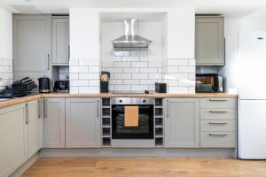 uma cozinha com armários brancos e um forno com placa de fogão em Luxury Two Bed Apartment with 55in TVs and Netflix em Headingley