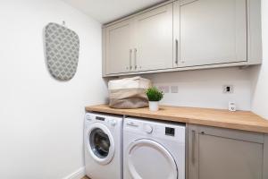 uma lavandaria branca com máquina de lavar e secar roupa em Luxury Two Bed Apartment with 55in TVs and Netflix em Headingley