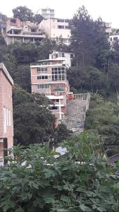 a building on a hill with trees and buildings at Aparto Suites 132, CA. in La Lagunita