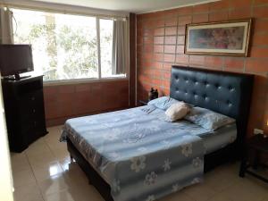 a bedroom with a bed with a blue blanket and a window at Aparto Suites 132, CA. in La Lagunita