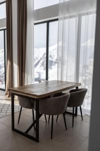 une table et des chaises en bois devant une fenêtre dans l'établissement New Gudauri View, à Goudaouri