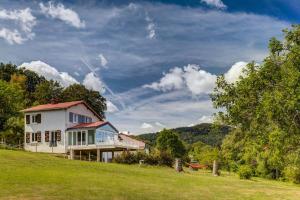 uma casa numa colina com um campo verde em L'Amphithéâtre des Volcans - Vue Puy de Dôme em Saint-Genès-Champanelle