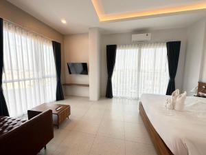 um quarto com uma cama grande e janelas grandes em Choe Hotel Banbueng em Ban Bung