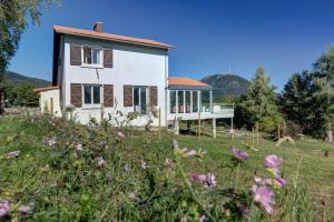 una casa en un campo con flores en primer plano en L'Amphithéâtre des Volcans - Vue Puy de Dôme, en Saint-Genès-Champanelle