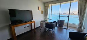 a living room with a television and a table with chairs at Nautilus Peninsula Piso 14 (Cerca de Todo) in Iquique