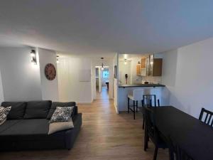 een woonkamer en een keuken met een bank en een tafel bij Le Nid Olympe - Metro - Wifi - Parking - Dream Host in Saint-Denis
