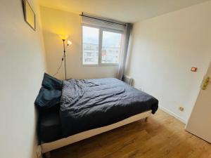 een slaapkamer met een bed in een kamer met een raam bij Le Nid Olympe - Metro - Wifi - Parking - Dream Host in Saint-Denis