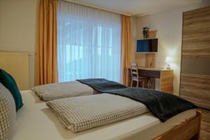 a bedroom with a bed with a desk and a window at HoFer am Zeitberg Ferienwohnung Echelsbach in Bad Kohlgrub