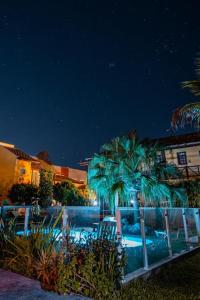 a pool with palm trees and chairs at night at pousada santa Genoveva Campeche 2 in Florianópolis