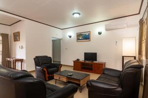 a living room with leather chairs and a television at Zeph self catering in Baie Lazare Mahé