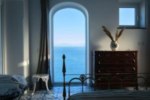 una camera da letto con vista sull'oceano da una grande finestra di Villa Alba - Amalfi Coast ad Amalfi