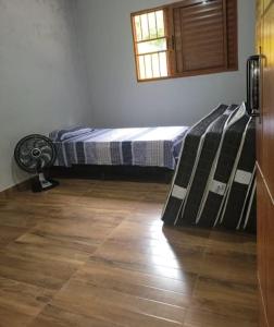a bedroom with a bed and a fan on a wooden floor at Chacara in Atibaia