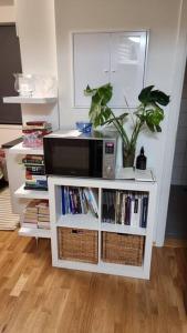 una estantería blanca con microondas y una planta en Studio apartment 10mins from Oslo Cent. station., en Oslo