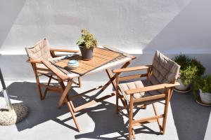 einen Holztisch und zwei Stühle auf einer Terrasse in der Unterkunft Chora Cozy Studios in Kythnos