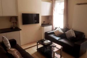 a living room with a black leather couch and a tv at Central Reading 4 Bedrooms Free Parking in Reading