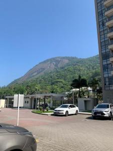 dos autos estacionados en un estacionamiento frente a una montaña en Flat apart - com vista panorâmica, en Río de Janeiro