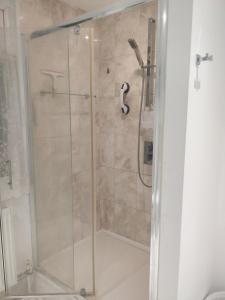 a shower with a glass door in a bathroom at Whites Place in Slades Green