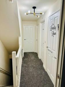 a hallway with two white doors and a staircase at Mo Apartment in Accrington