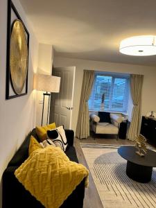 a living room with a black couch and a yellow blanket at Mo Apartment in Accrington