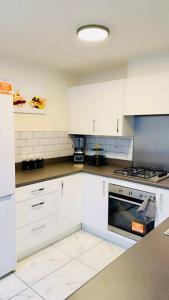 uma cozinha com armários brancos e um forno com placa de fogão em Mo Apartment em Accrington