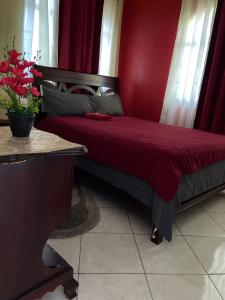 a bedroom with a bed with a red wall at Elite's Ocean View in Montego Bay