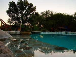 uma piscina de água com escorrega e árvores em Posada La Valentina em Villa Las Rosas