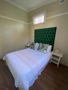 a bedroom with a large bed with a green headboard at Othandweni Holiday Home in Durban