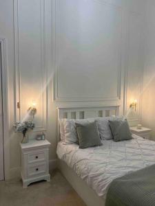 a white bedroom with a bed and a night stand at Victorian Stay in Ocean village in Southampton