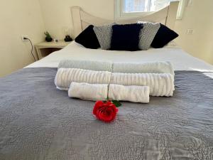ein Bett mit zwei Handtüchern und einer Rose drauf in der Unterkunft Beachfront Studio, fully equipped in Netanya