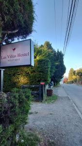 un cartel para un hostal Las Vinneys al lado de una carretera en Las Viñas Hostel Boutique en San Carlos de Bariloche