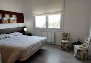 a bedroom with a bed and a chair and a window at Casa con Jardín entre Toledo y Puy du Fou in Toledo