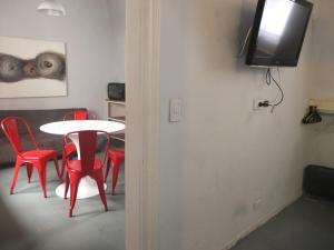 a room with a table and red chairs and a tv at Casa San Telmo 3081 in Buenos Aires